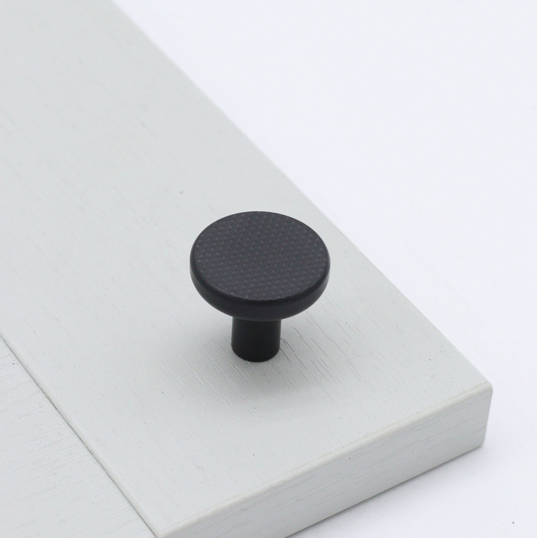 Bonnington button rounded knob with knurl detail in ceramic black on pale grey shaker cabinetry door