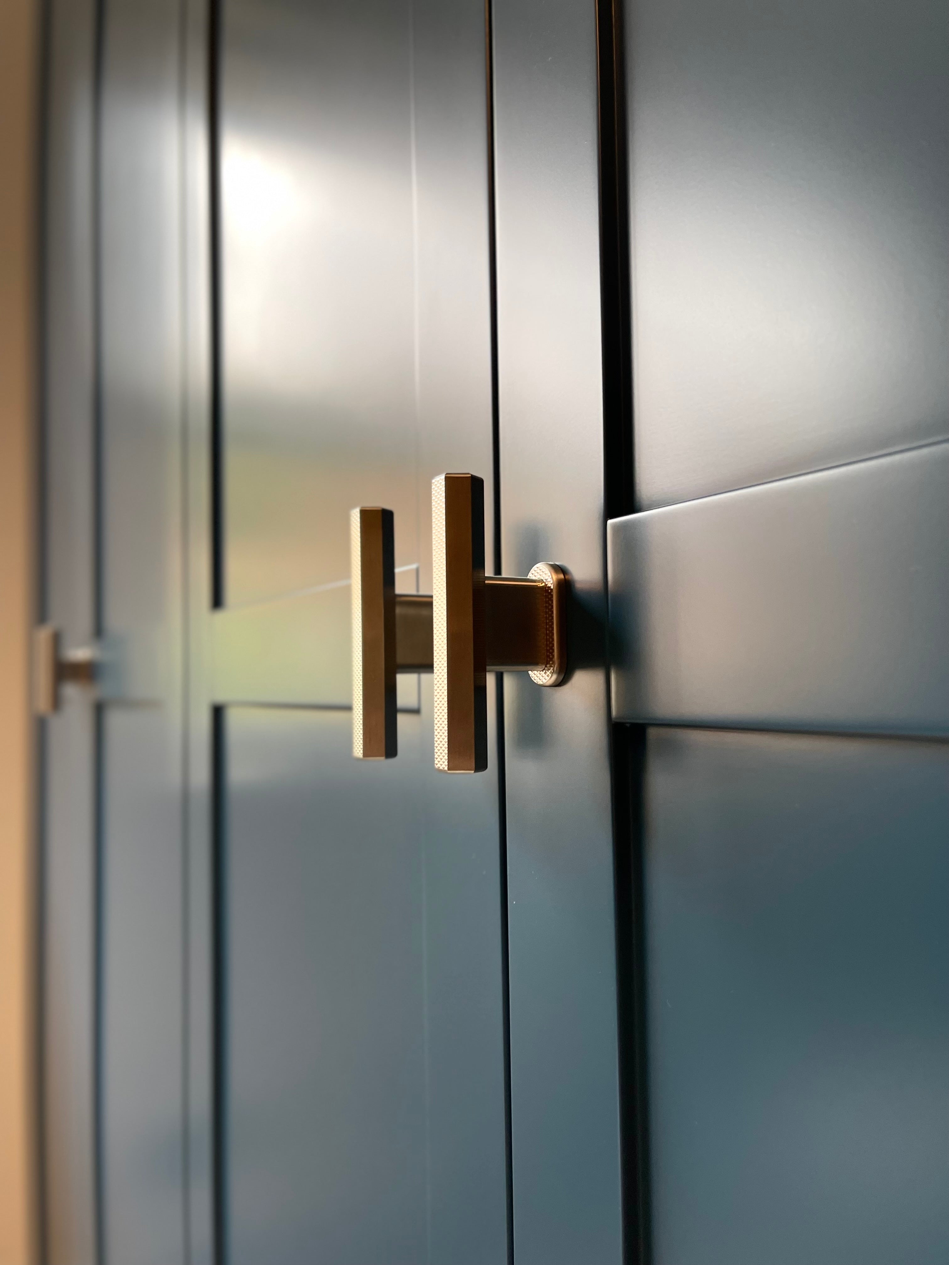 sennen polished brass t-bar handle pulls with hex knurling on dark blue wardrobe cabinetry