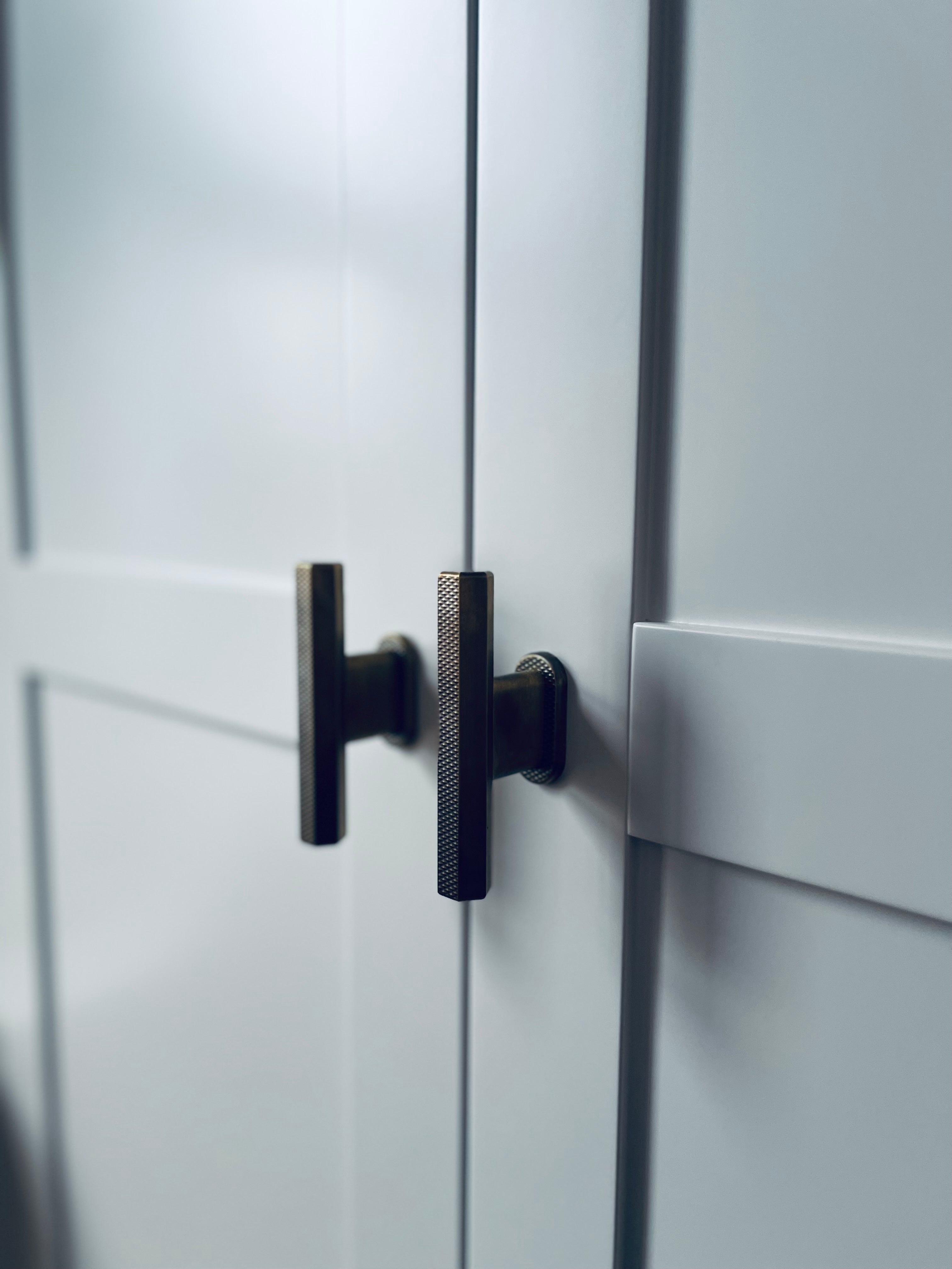 flat knurled hex pull bar t-bar handle in antique bronze on white modern shaker cabinetry for wardrobes
