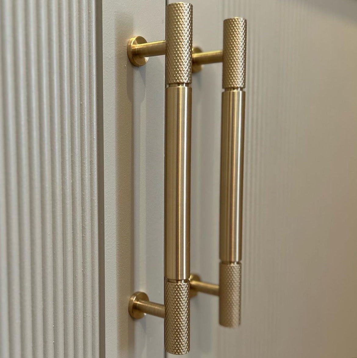 Bambino Grande pull bar with signature knurl ends in satin brass on dark cream shaker cabinetry - photo by Inner City Carpentry Ireland