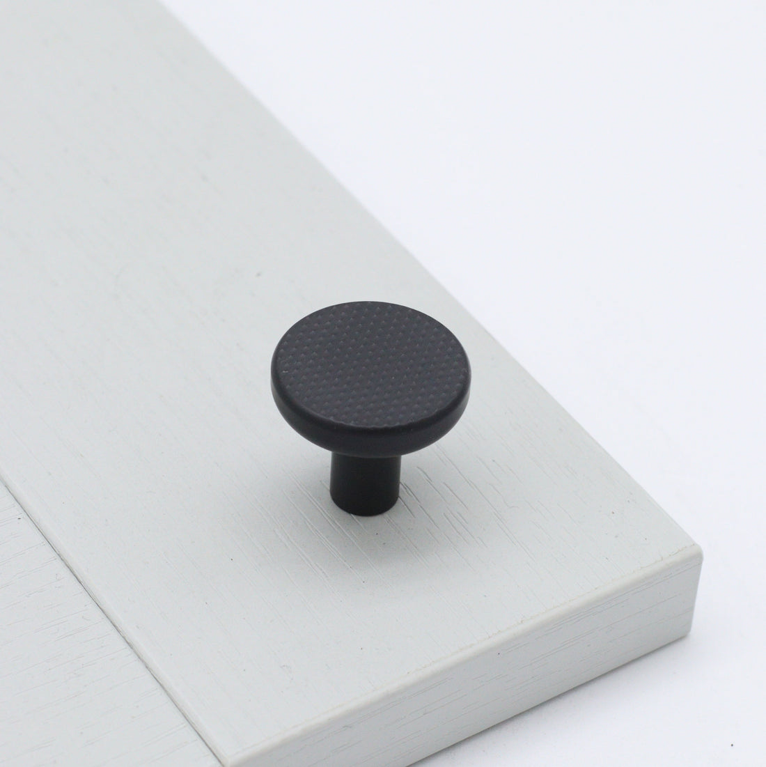 Bonnington button rounded knob with knurl detail in ceramic black on pale grey shaker cabinetry door 