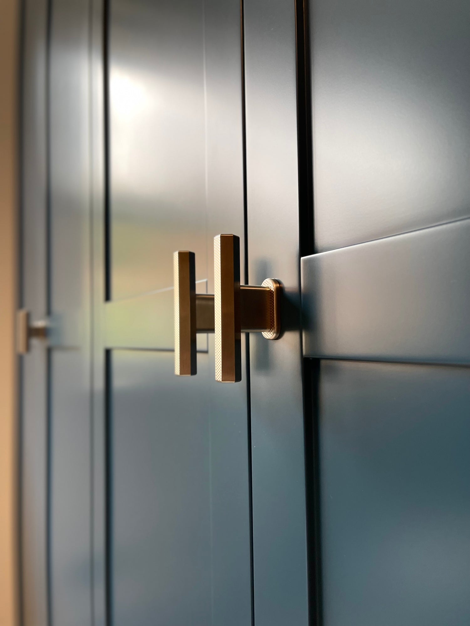 sennen polished brass t-bar handle pulls with hex knurling on dark blue wardrobe cabinetry 