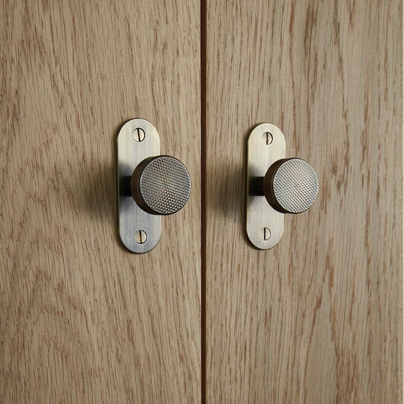 antique bronze (brushed brass) flat knurled pull knob with rounded back plates on oak wooden cabinetry door