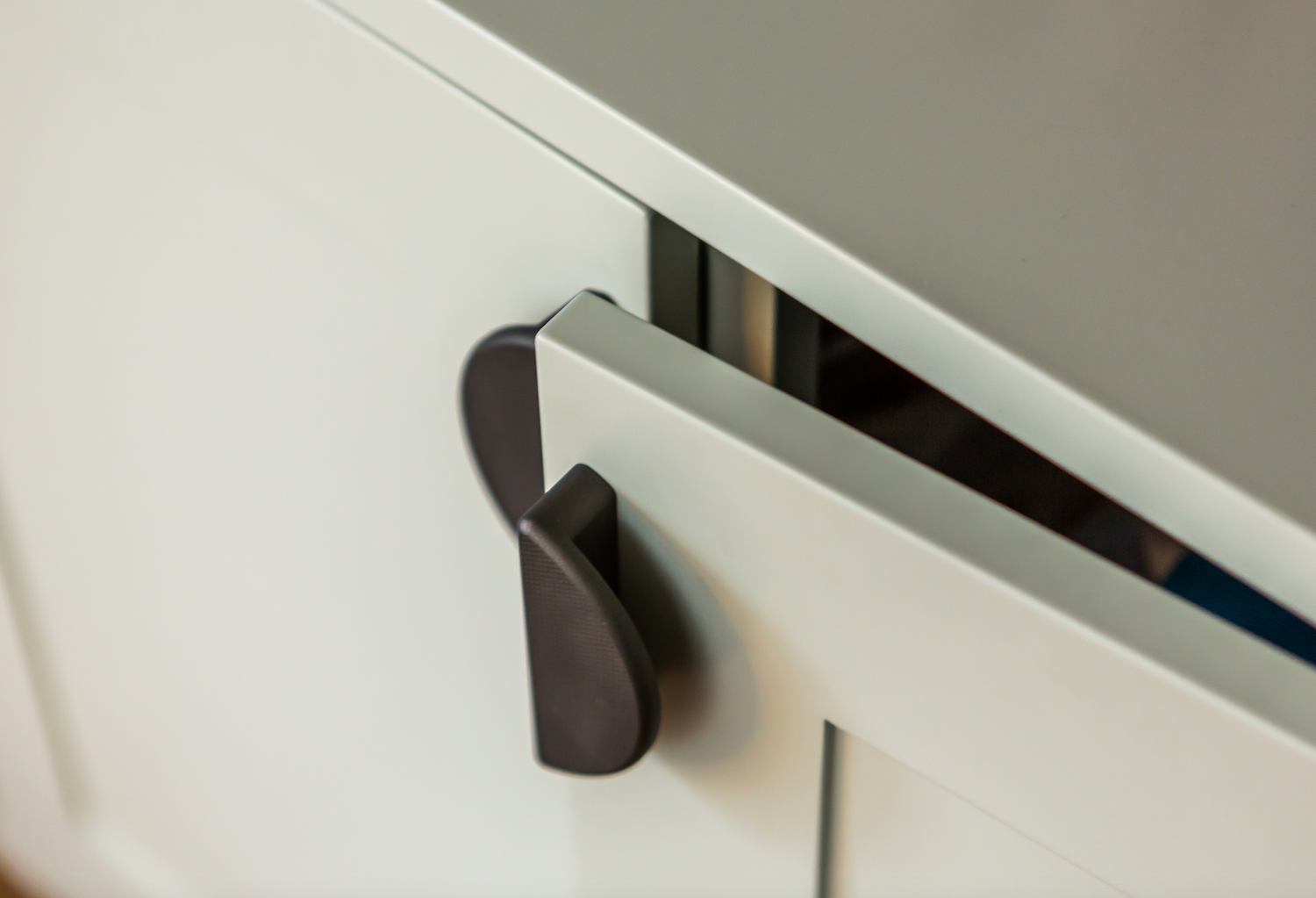 crescent shaped half moon handle in cerakote midnight bronze with knurl detail on white shaker cabinetry doors